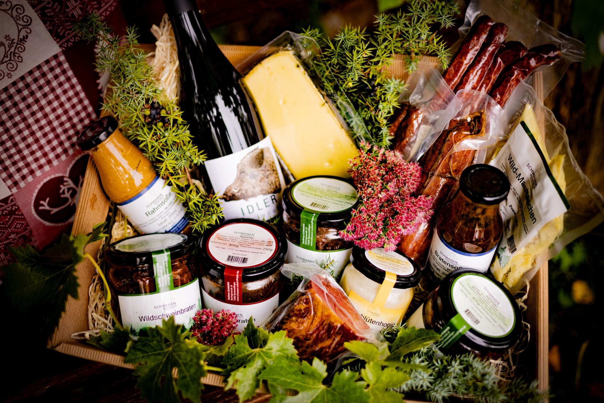 Geschenkkorb mit verschiedenen Gläsern Braten, Maultaschen, Honig, Pfeffer-Beißer, Flasche Wein vom Idler, verschiedene Soßen, Stück Käse.