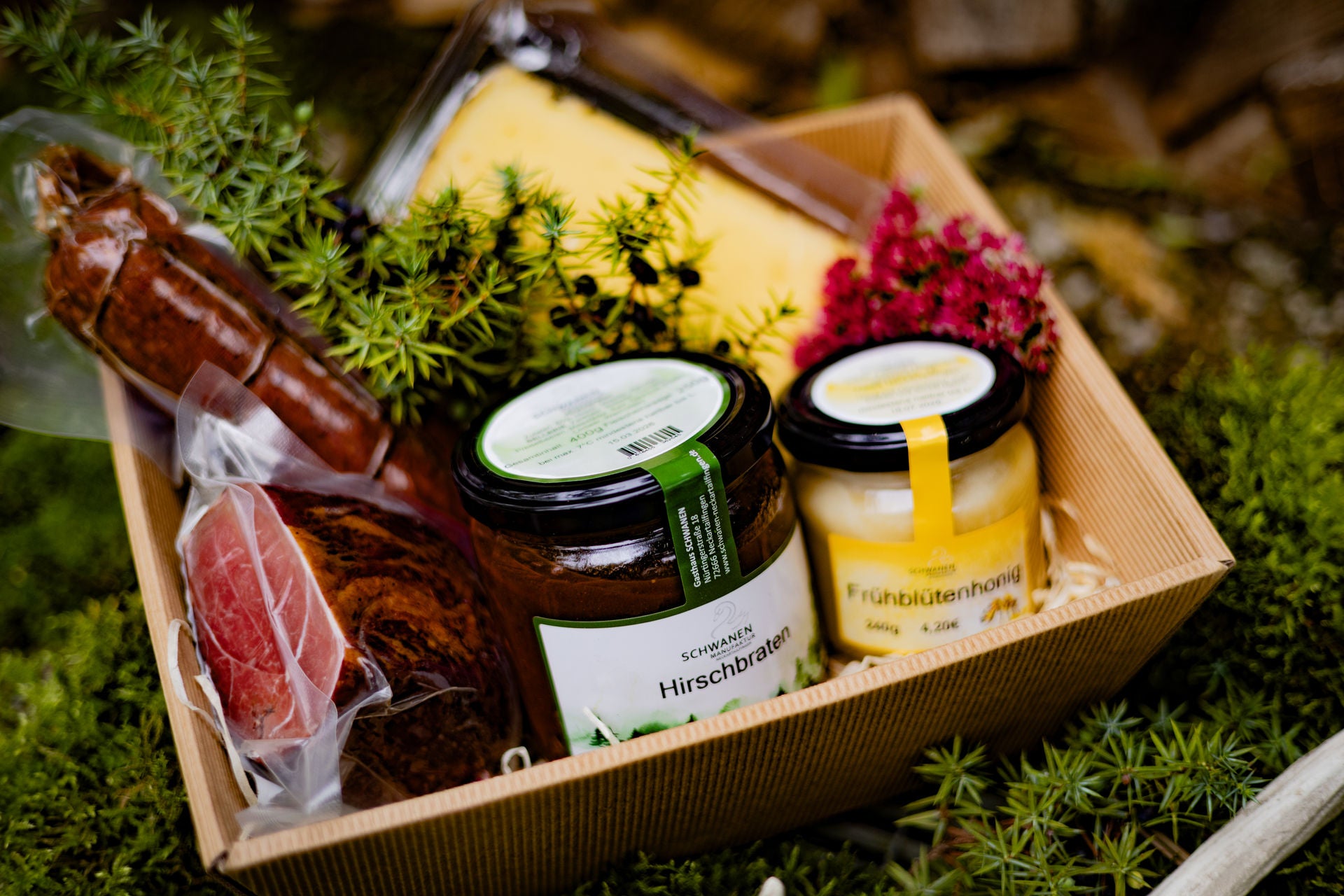 Geschenkkorb mit Hirschbraten, kleinem Honig, Schinken, Wildsalami und Bergkäse